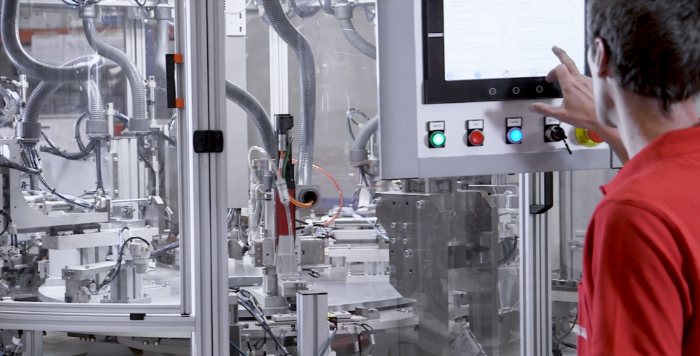 Operario trabajando en una máquina automatizada de montaje, ejemplo de capacidad interna en proyectos de automoción.