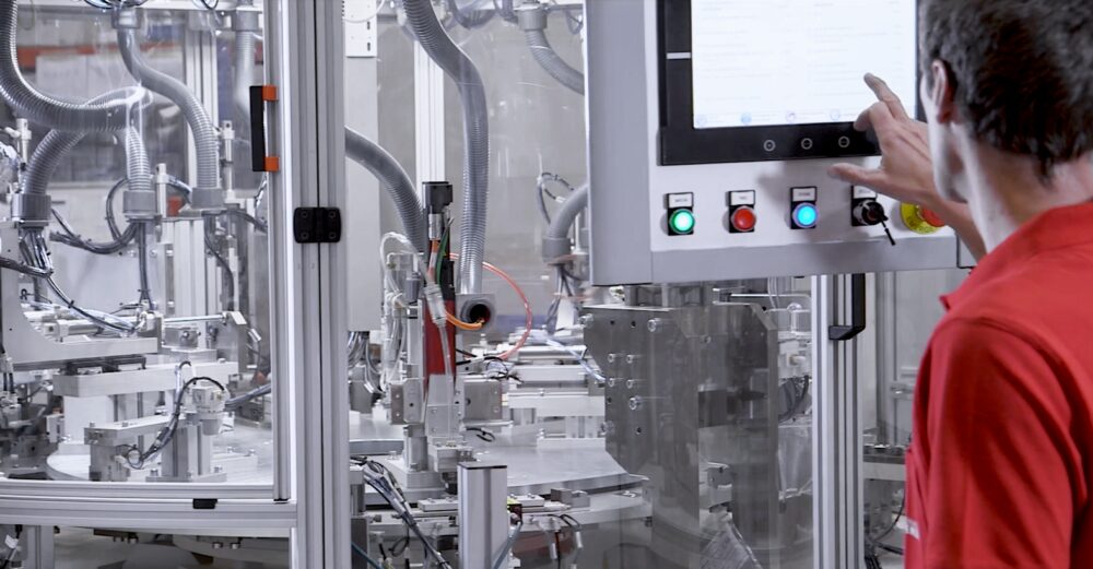 Operario trabajando en una máquina automatizada de montaje, ejemplo de capacidad interna en proyectos de automoción.