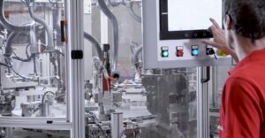 Operario trabajando en una máquina automatizada de montaje, ejemplo de capacidad interna en proyectos de automoción.