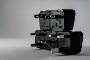 Adaptadores eléctricos apilados con distintas clavijas metálicas mostrados en primer plano.